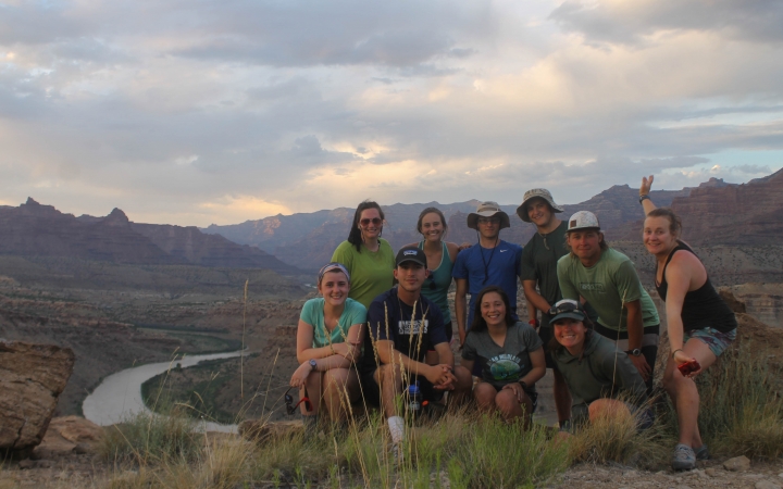 A group of students pose for a photo on an overlook above a winding river